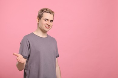 Happy man inviting to come in against pink background, space for text