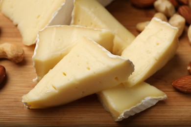 Photo of Tasty Camembert cheese with nuts on wooden table, closeup