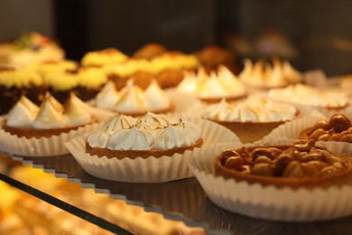 Different tasty tartlets on counter in bakery shop, closeup. Space for text