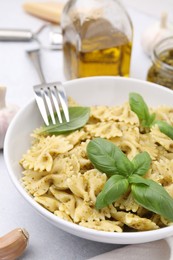 Photo of Delicious pasta with pesto sauce and basil served on light table, closeup