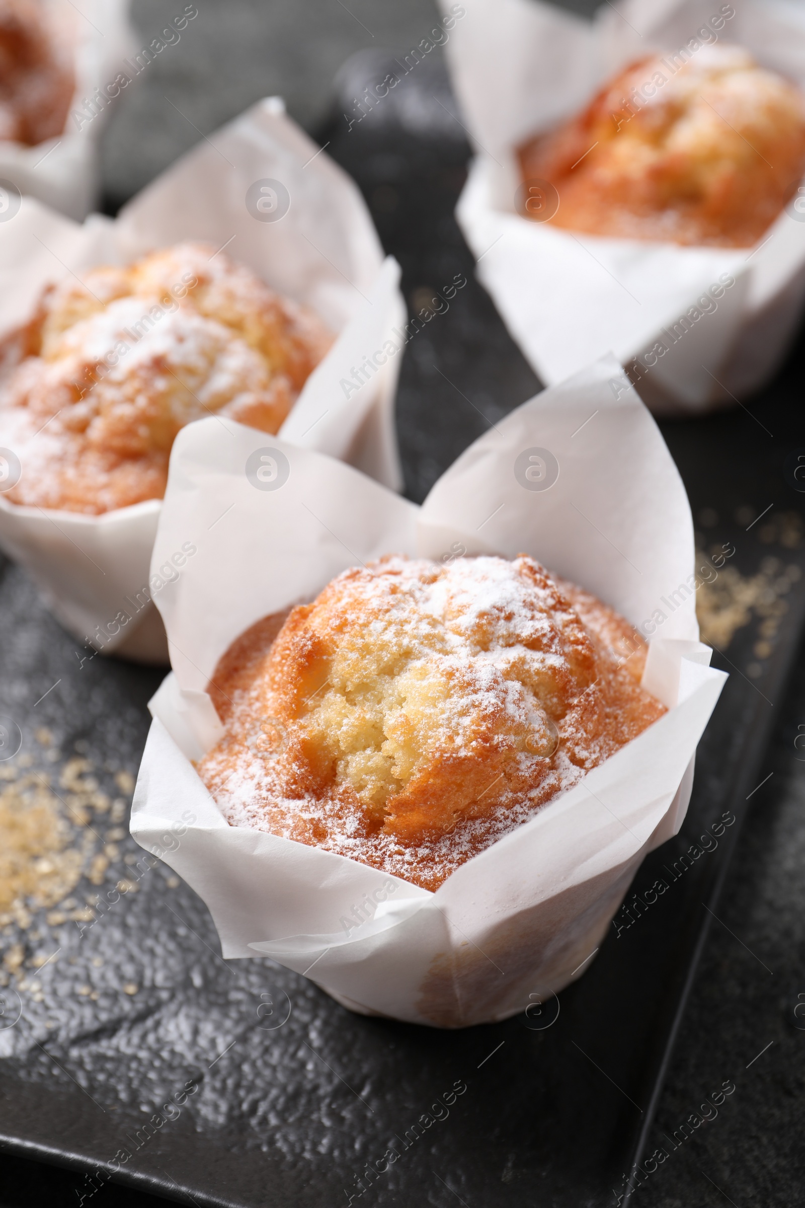 Photo of Delicious muffins with powdered sugar on table, closeup