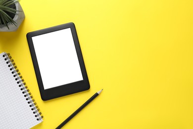 Photo of Modern e-book reader, plant, notebook and pencil on yellow background, flat lay. Space for text