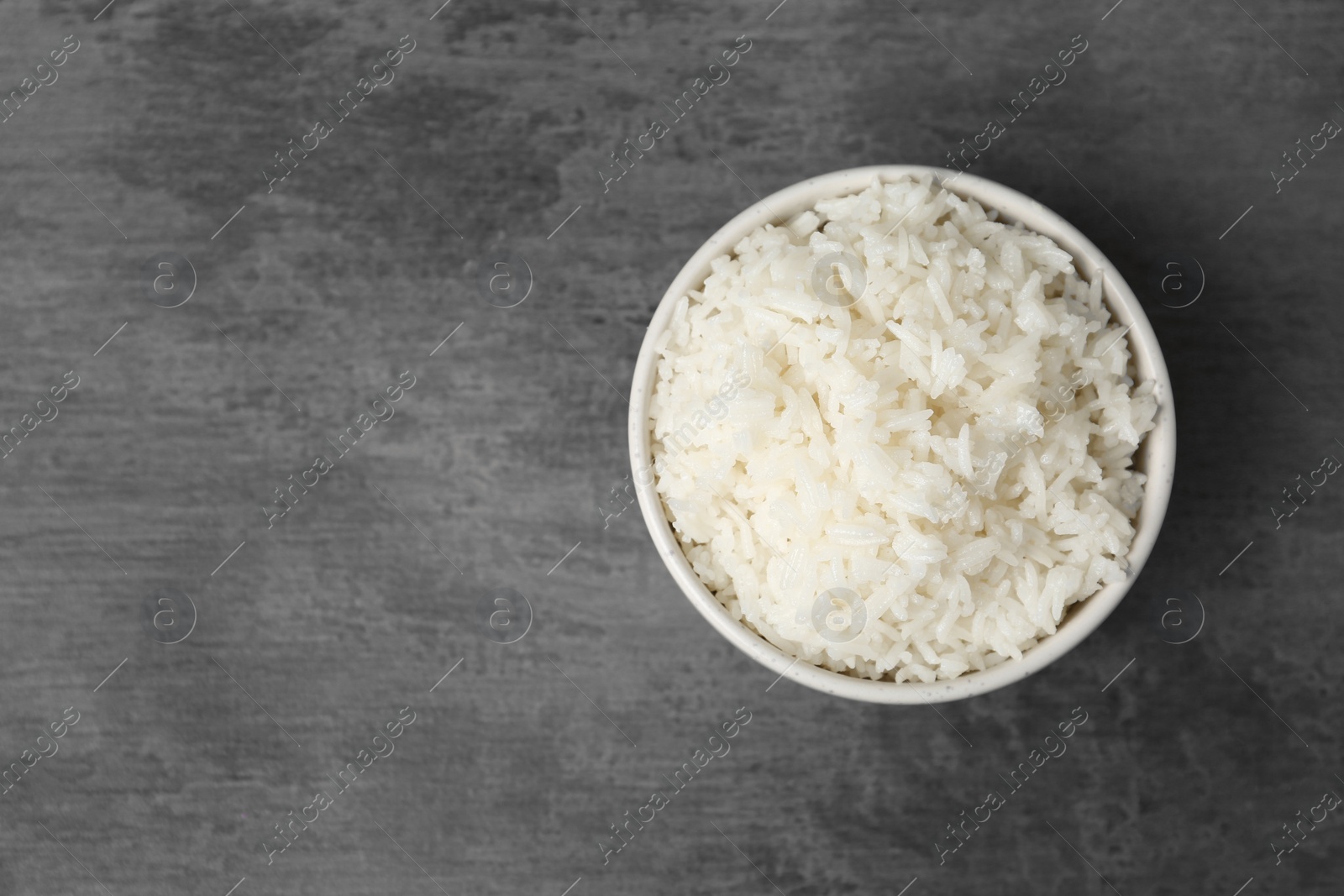 Photo of Boiled rice in bowl on grey background, top view with space for text