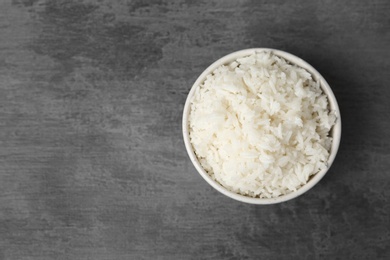 Photo of Boiled rice in bowl on grey background, top view with space for text