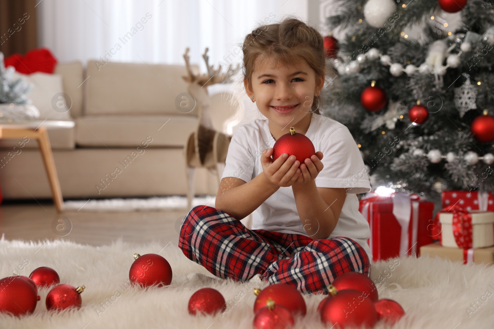 Photo of Cute little girl with box of Christmas balls at home