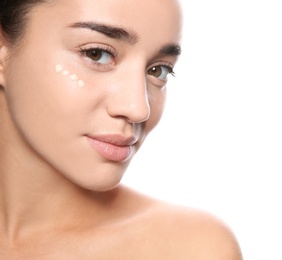 Portrait of young woman with liquid foundation on her face against white background