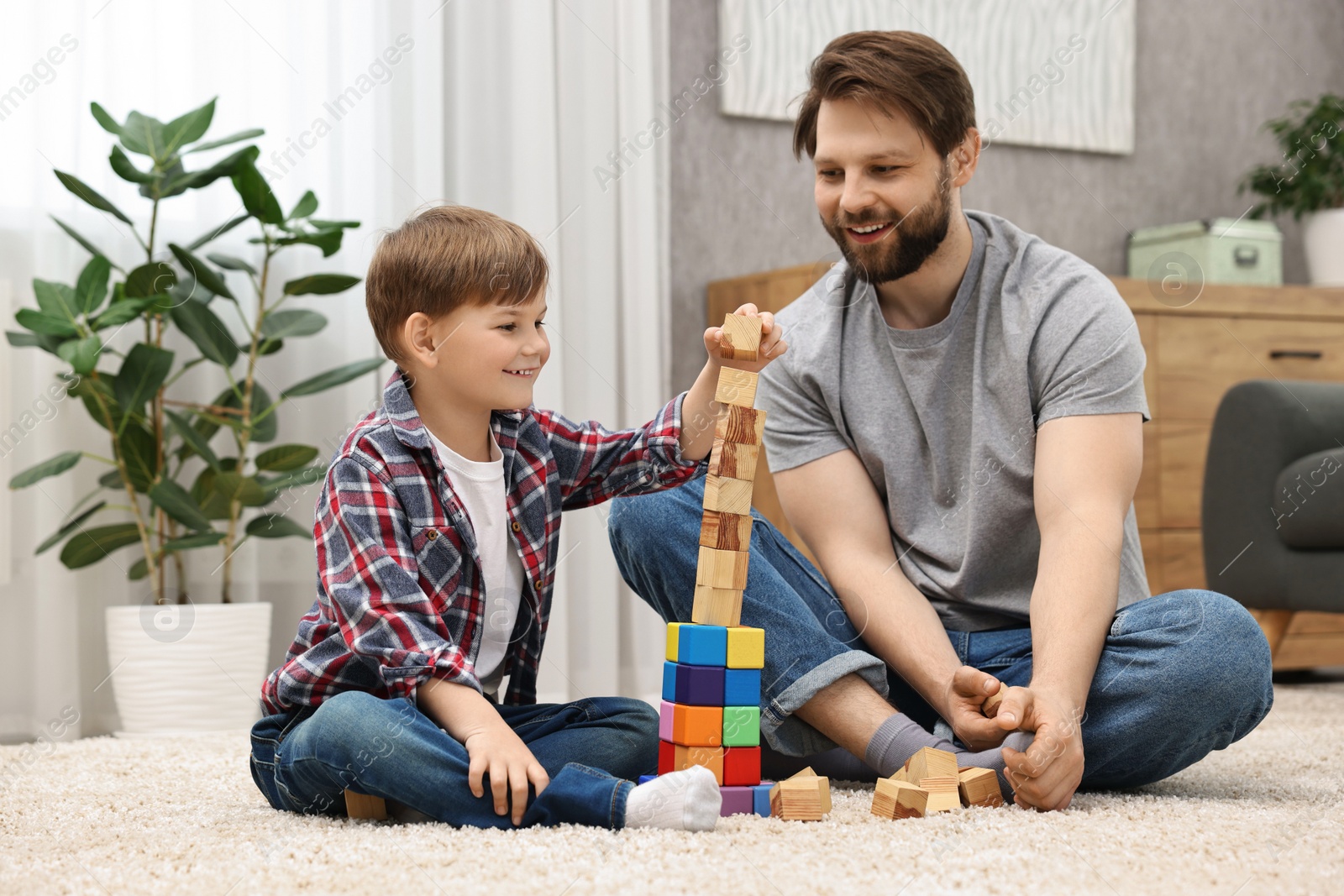 Photo of Happy dad and son building tower with cubes at home