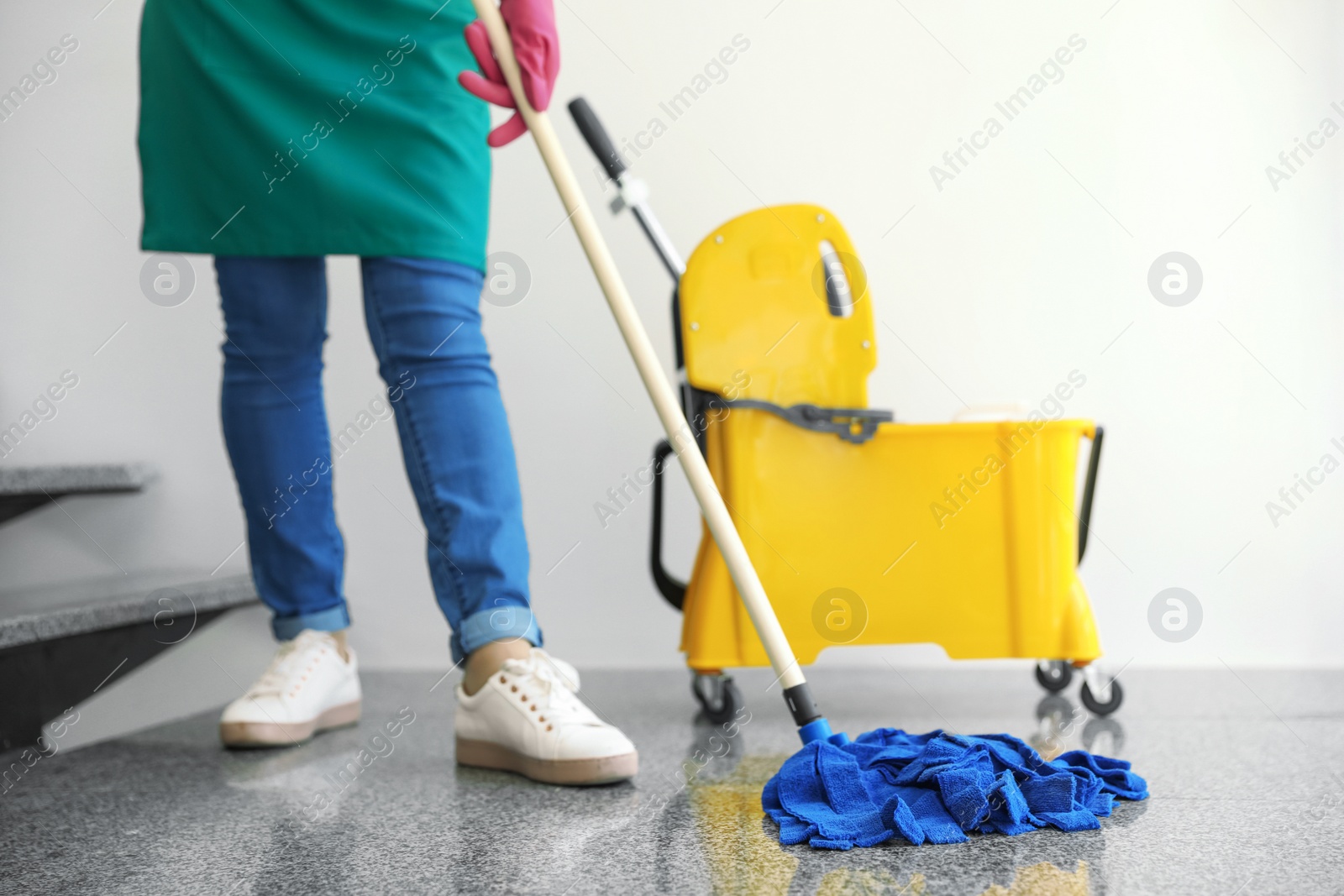 Photo of Young woman with mop cleaning stairs