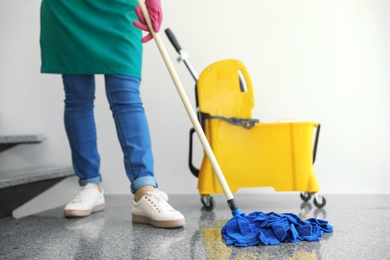 Photo of Young woman with mop cleaning stairs