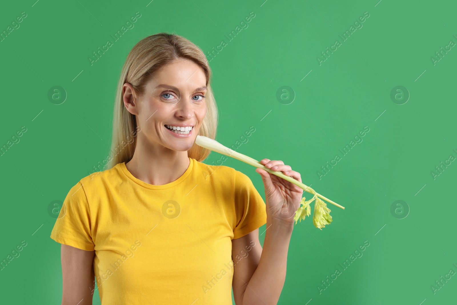 Photo of Woman with fresh celery stem on green background. Space for text