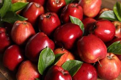 Photo of Fresh ripe red apples with leaves as background, closeup