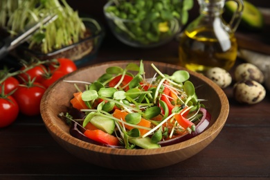 Photo of Salad with fresh organic microgreen in bowl on wooden table, closeup