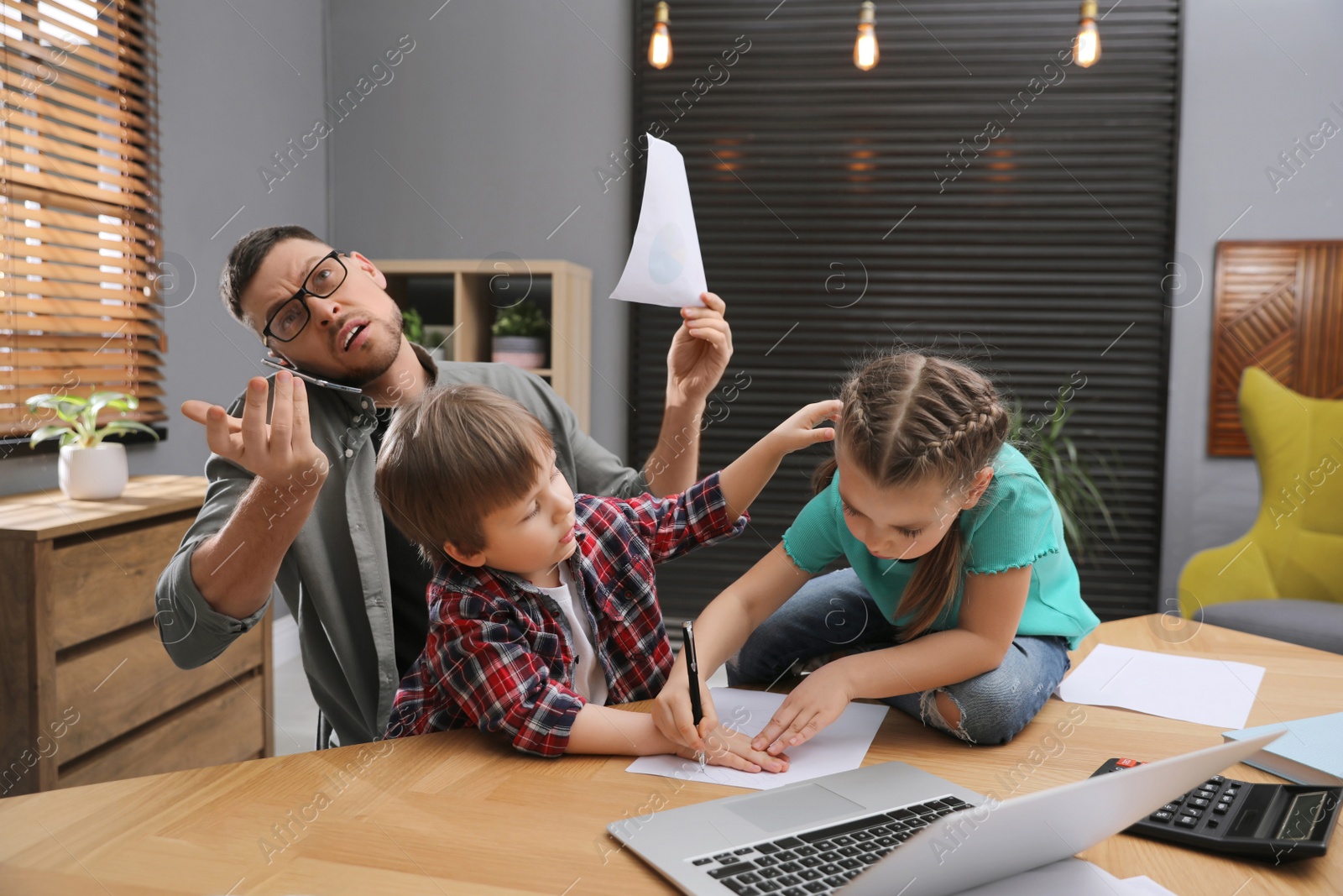 Photo of Overwhelmed man combining parenting and work at home