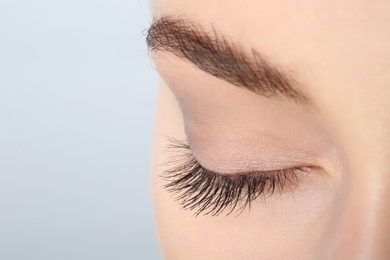 Photo of Young woman with beautiful natural eyelashes on light background, closeup. Space for text