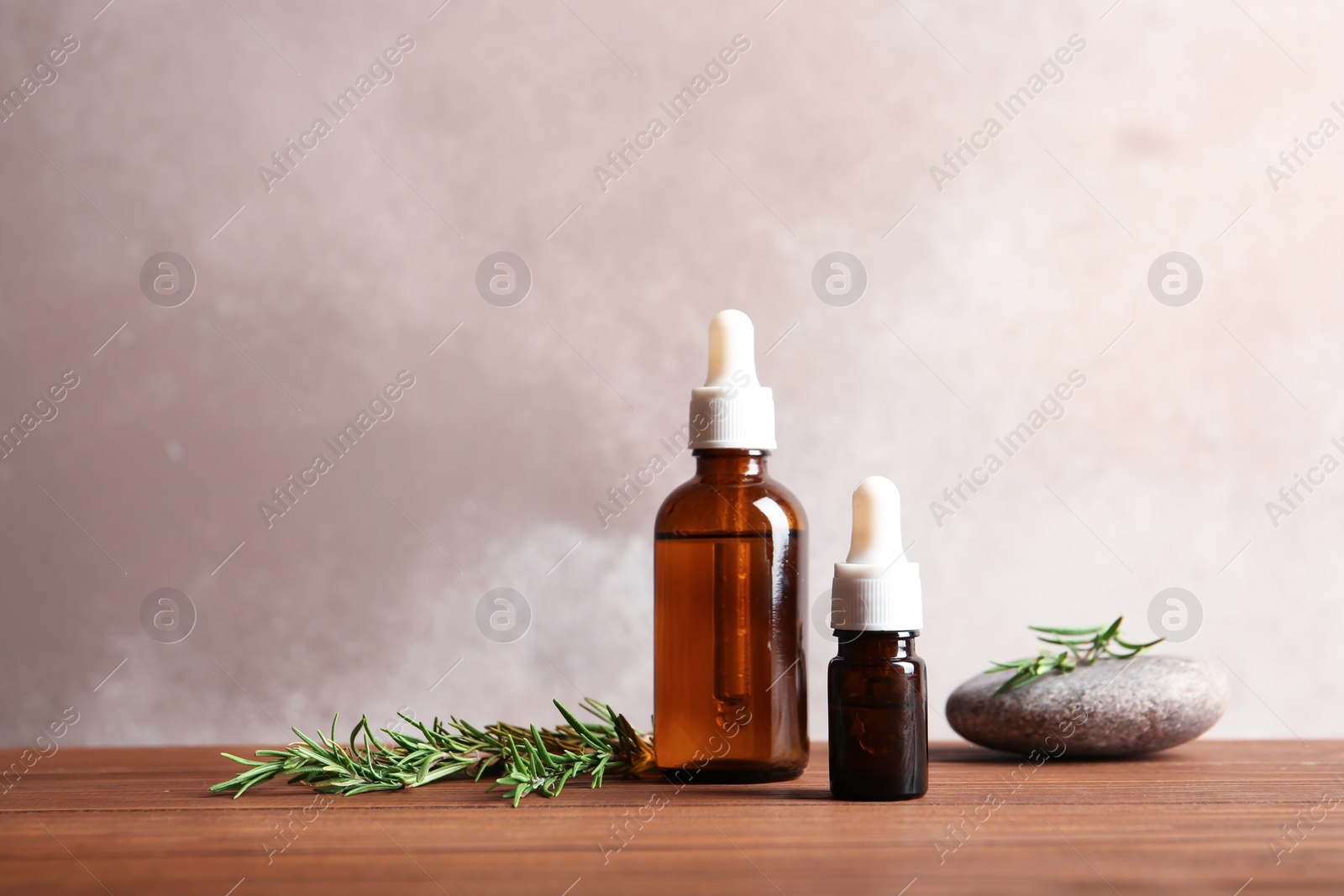 Photo of Bottles with fresh rosemary oil on table