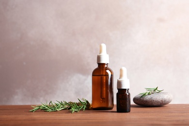 Bottles with fresh rosemary oil on table