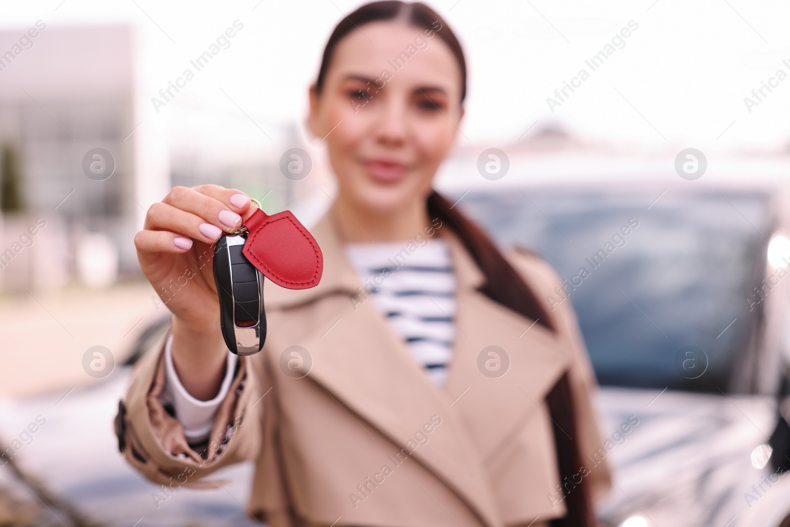 Photo of Woman holding car flip key near her vehicle outdoors, selective focus