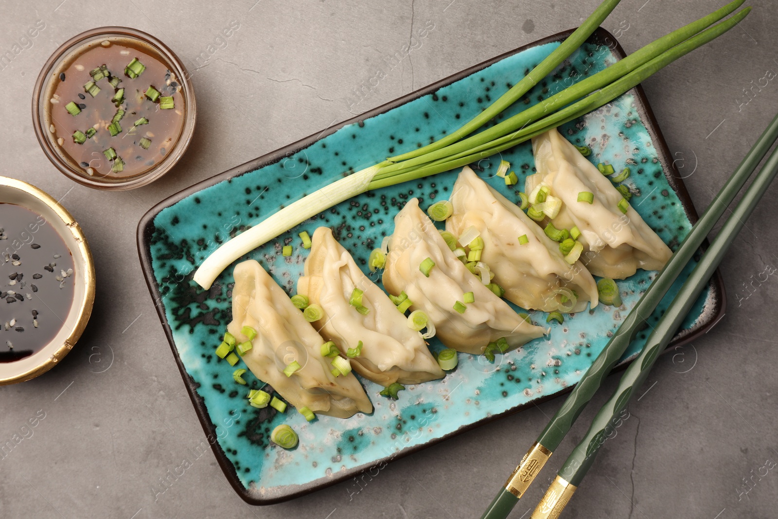 Photo of Delicious gyoza (asian dumplings) served on gray table, flat lay.