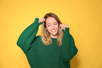 Happy young woman wearing warm sweater on yellow background