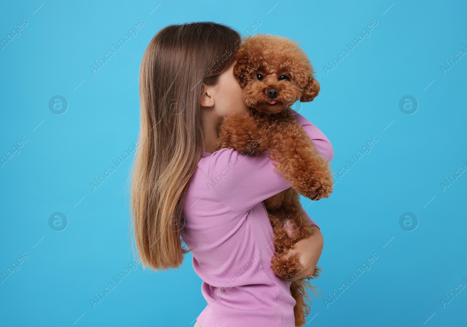 Photo of Little child with cute puppy on light blue background. Lovely pet