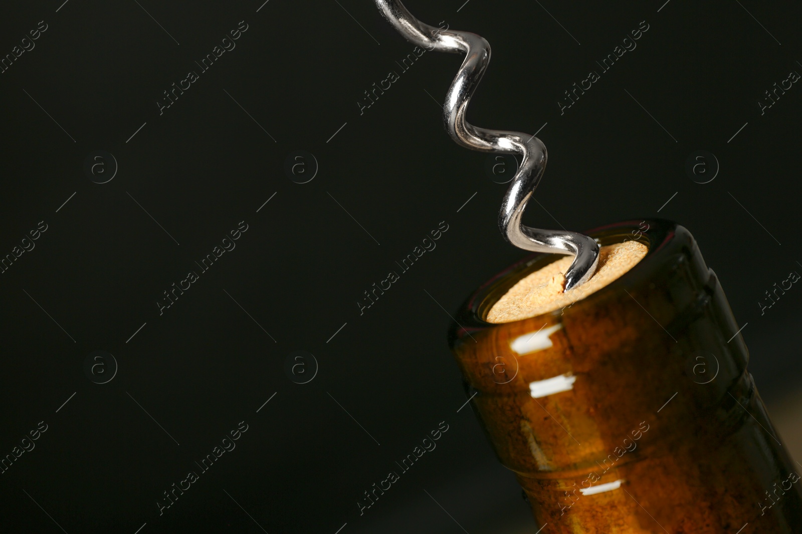 Photo of Bottle of wine and corkscrew on dark background, space for text