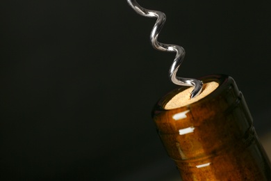 Photo of Bottle of wine and corkscrew on dark background, space for text