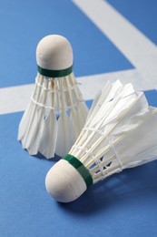 Feather badminton shuttlecocks on blue background, closeup