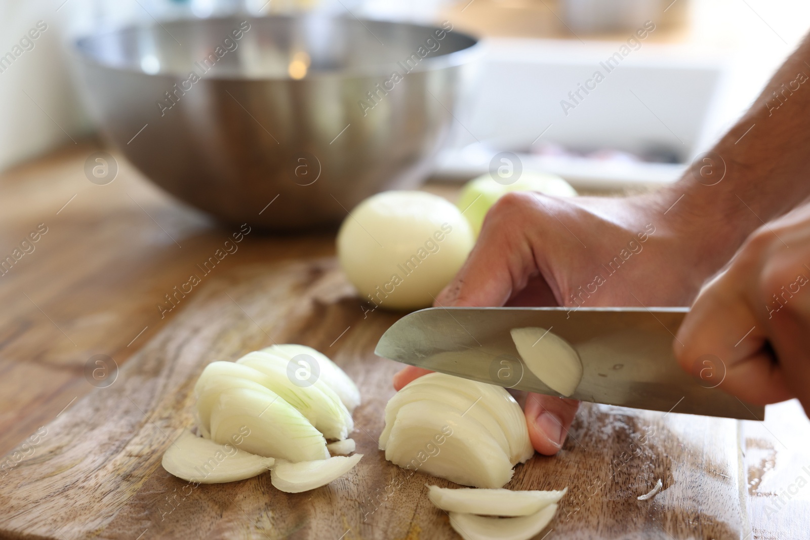 Photo of Woman cutting fresh ripe onion on wooden board, closeup. Space for text