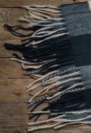 Soft checkered scarf on wooden table, top view