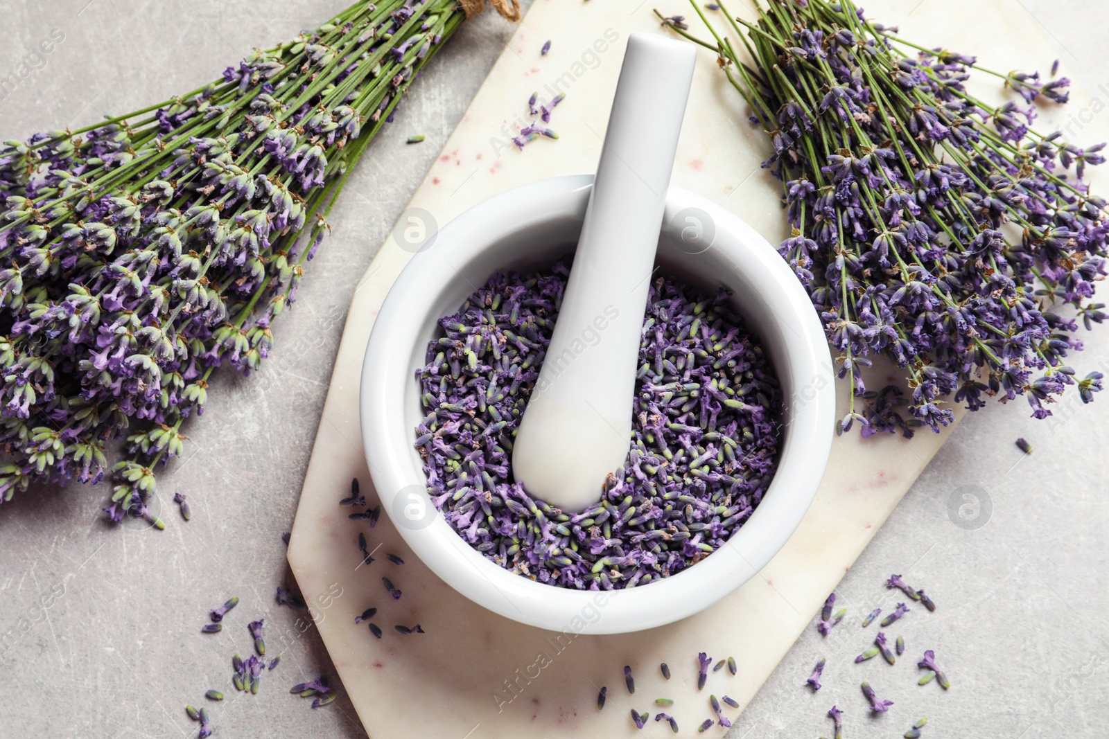 Photo of Mortar and pestle with lavender flowers on grey stone background, top view. Natural cosmetic