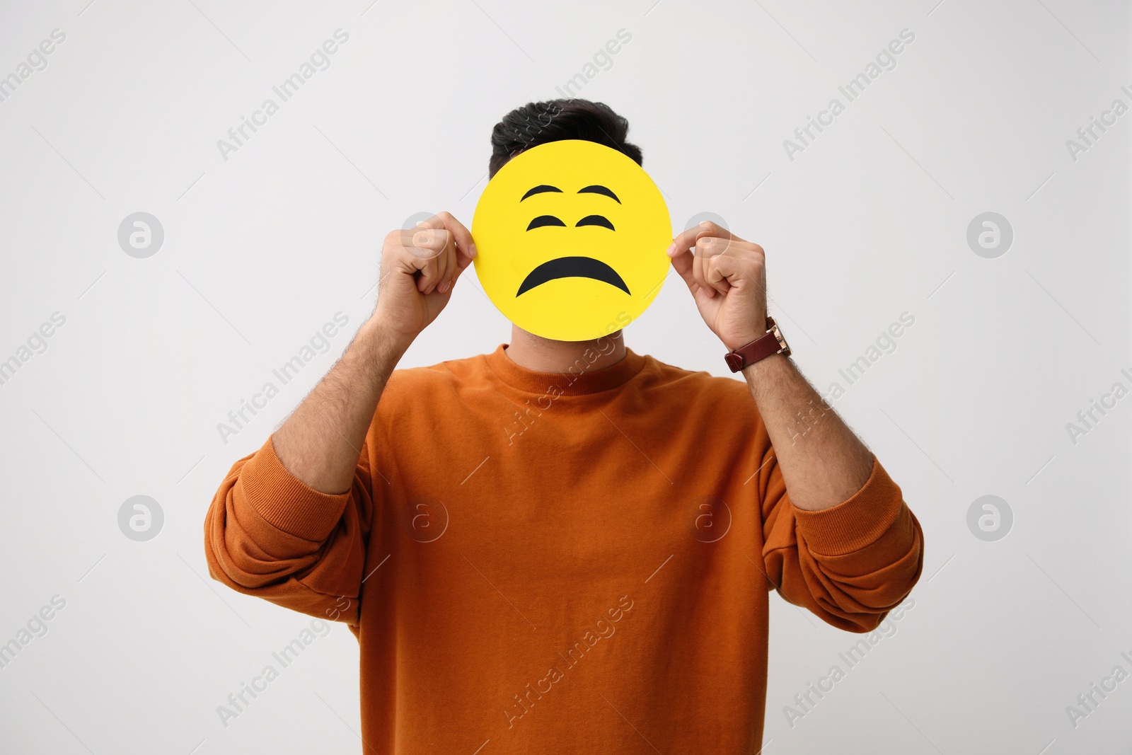 Image of Man hiding behind card with sad face on white background