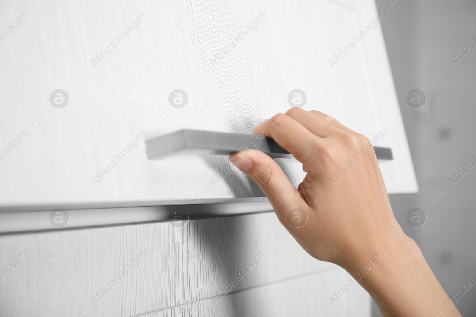 Photo of Woman opening cabinet door at home, closeup