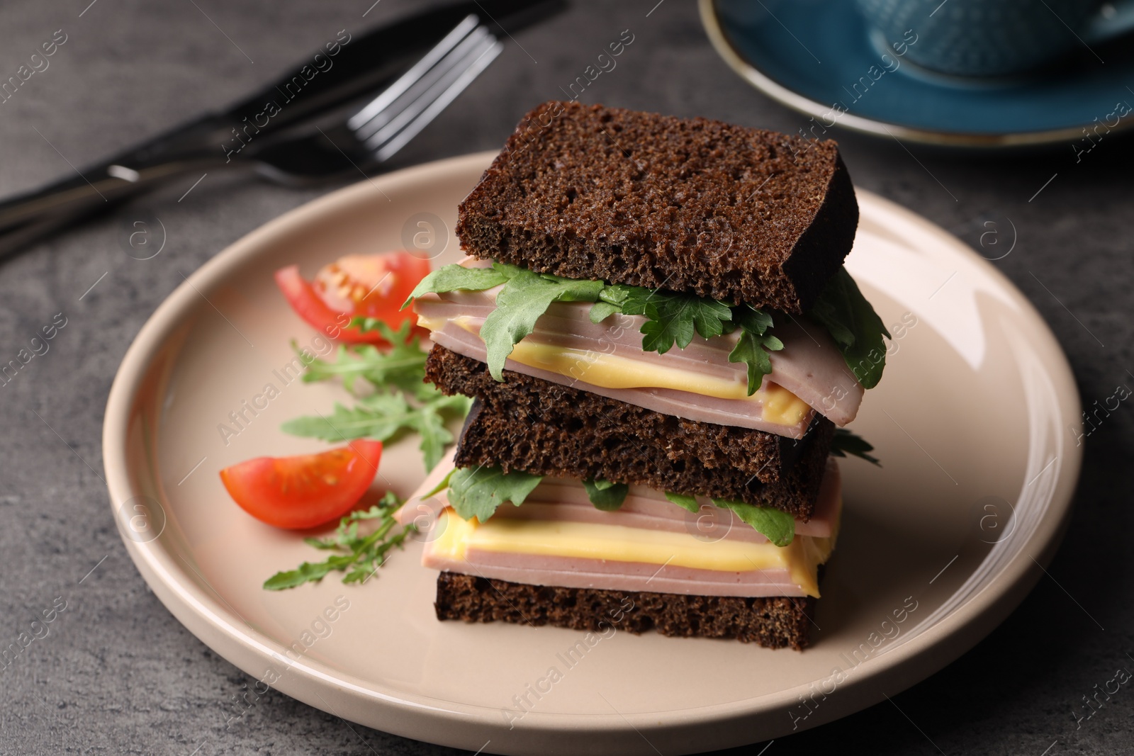 Photo of Delicious sandwiches with boiled sausage, tomato, cheese and arugula on grey table, closeup