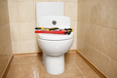 Different plumber's tools on toilet seat lid indoors