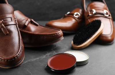 Photo of Shoe care accessories and footwear on black slate background, closeup