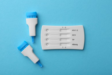 Photo of Disposable multi-infection express test and lancets on light blue background, flat lay