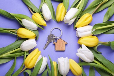 Beautiful spring flowers and key with trinket in shape of house on violet background, flat lay