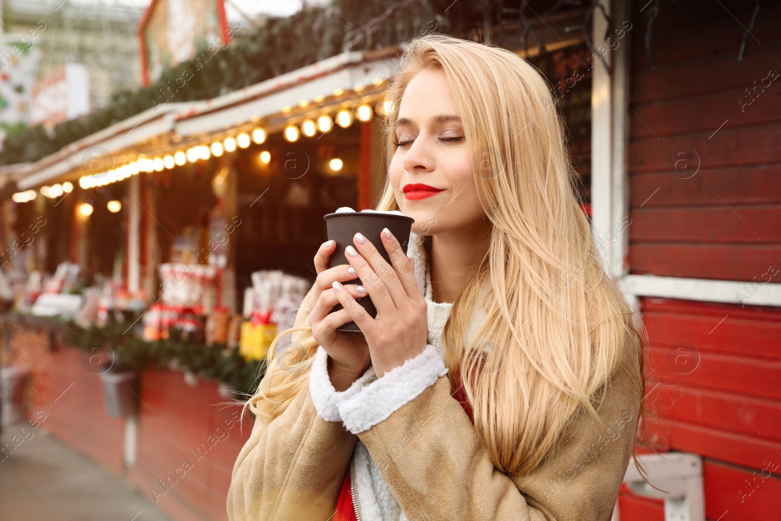 Photo of Young woman with hot drink at Christmas fair