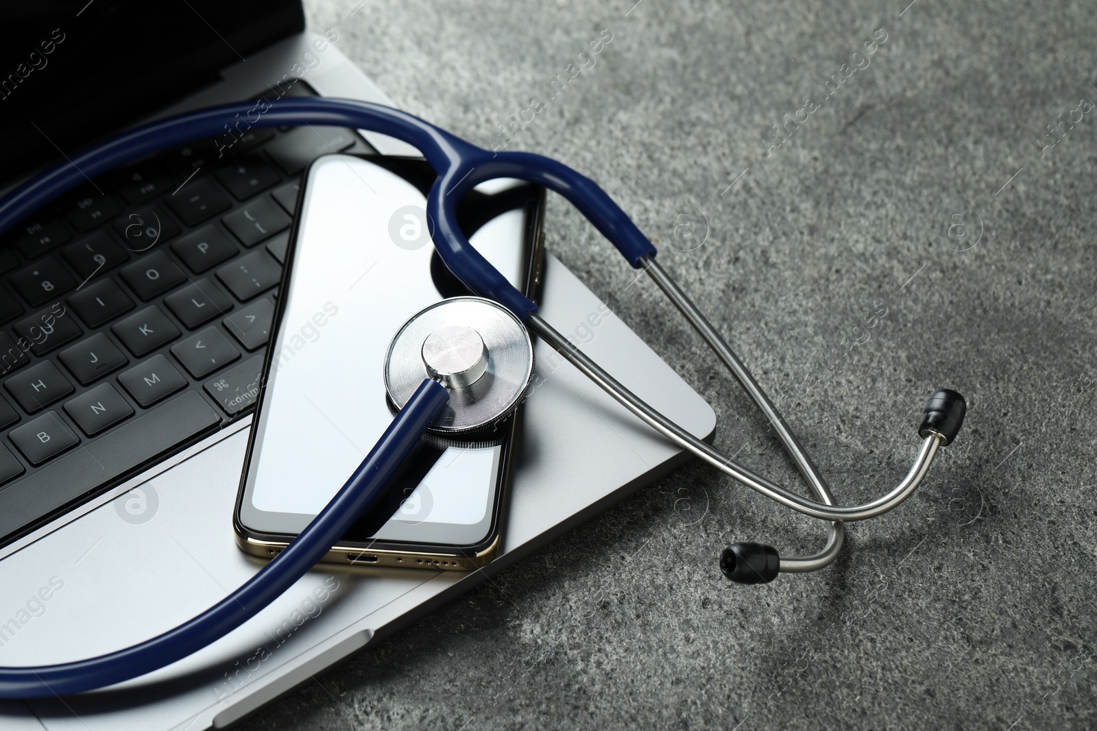 Photo of Modern electronic devices and stethoscope on grey table