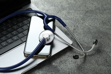 Photo of Modern electronic devices and stethoscope on grey table