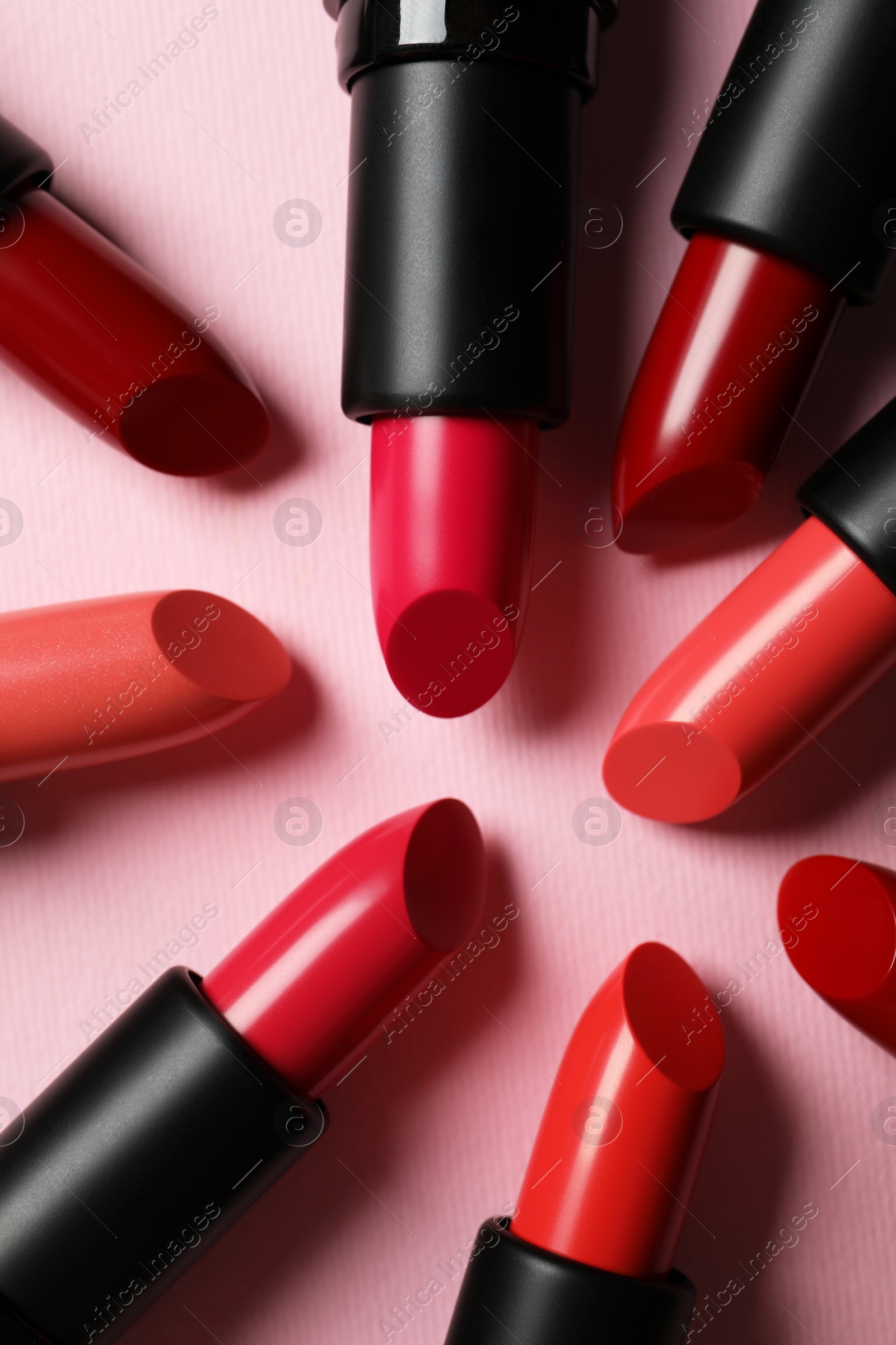 Photo of Many bright lipsticks on pink background, flat lay