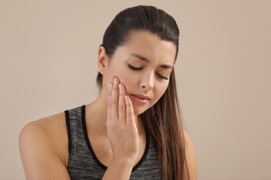 Young woman with sensitive teeth on color background. Space for text