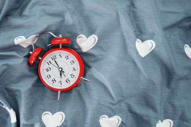 Photo of Analog alarm clock on bed, top view. Time of day