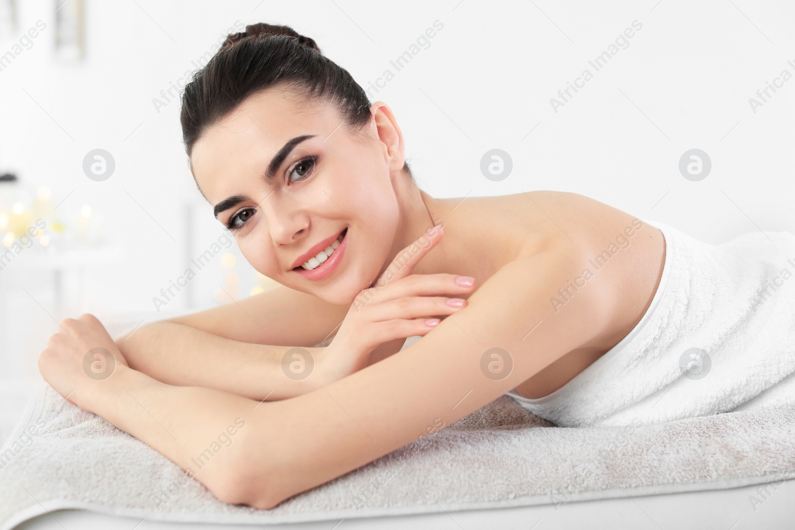 Photo of Young woman lying on massage table in spa salon