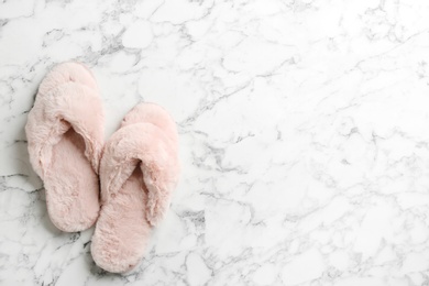 Photo of Pair of soft slippers on white marble background, flat lay. Space for text