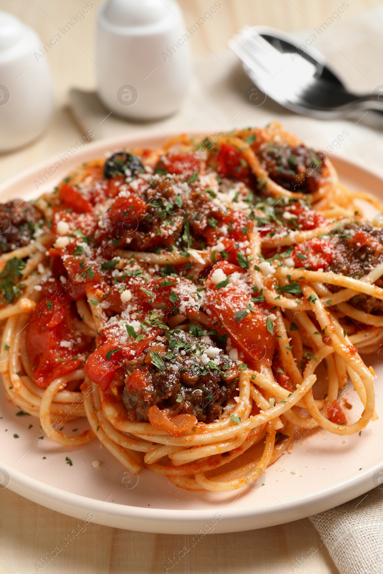 Photo of Delicious pasta with meatballs and tomato sauce served on wooden table, closeup