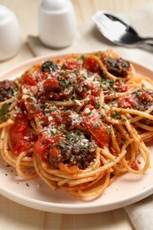 Photo of Delicious pasta with meatballs and tomato sauce served on wooden table, closeup
