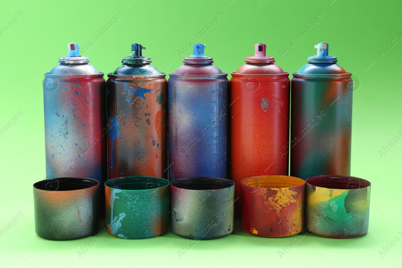 Photo of Many spray paint cans with caps on green background