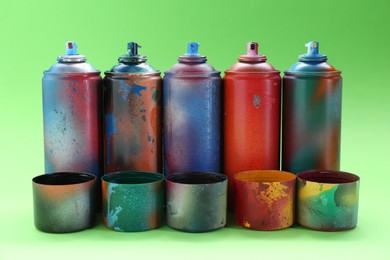 Photo of Many spray paint cans with caps on green background