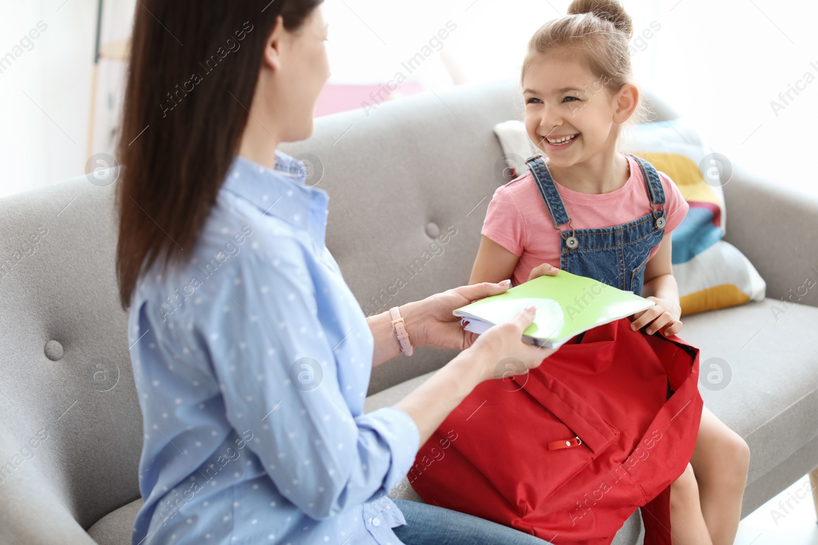 Photo of Young woman helping her little child get ready for school at home